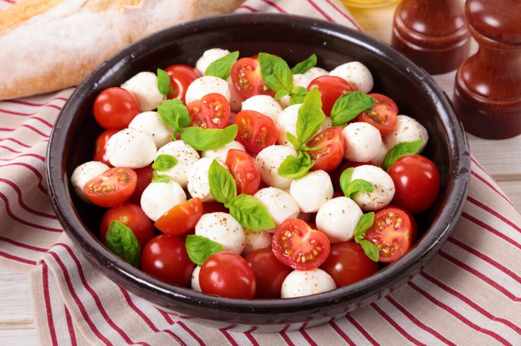 Caprese Salad With Mozzarella, Cherry Tomatoes And Basil Leaves